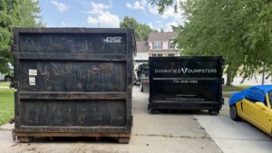 Local dumpster vs national dumpster company truck comparison in driveway
