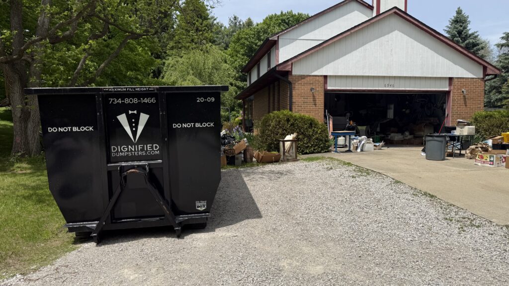 Family moving boxes into a home with a driveway-friendly dumpster rental nearby