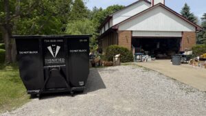 Family moving boxes into a home with a driveway-friendly dumpster rental nearby
